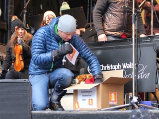Adrian Küpfer mit Paket auf der Bühne.