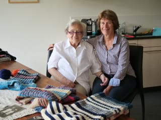 Zwei Frauen an einem Esstisch mit Strickarbeiten. Zwei Frauen an einem Esstisch mit Strickarbeiten.