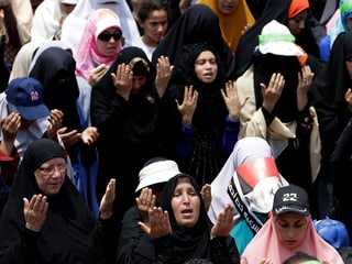 Frauen halten während dem Gebet die Arme in die Höhe