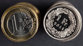 Ein Einfränkler liegt neben einem Ein-Euro-Stück.