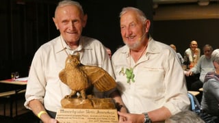 Zwei Männer und ein Pokal in Form eines Adlers.