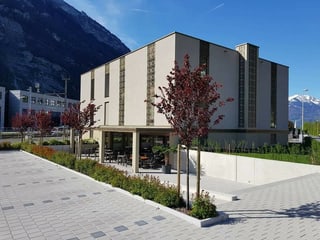 Ein rechteckiges, beiges Gebäude. Im Hintergrund schneebedeckte Berge. Ein rechteckiges, beiges Gebäude. Im Hintergrund schneebedeckte Berge.