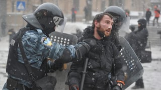 Polizisten verhaften einen Demonstranten in Kiew zurück.
