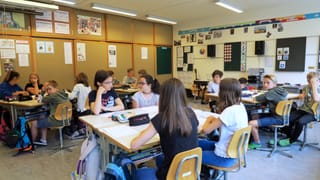 Mädchen und Knaben sitzen in einem Schulzimmer Mädchen und Knaben sitzen in einem Schulzimmer