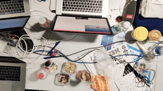 Ein Tisch von oben gesehen, darauf Computer, Kabel, Essenresten und Getränke. Ein Tisch von oben gesehen, darauf Computer, Kabel, Essenresten und Getränke.