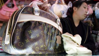 Chinesische Verkäuferin bietet eine gefälschte Louis-Vuitton-Tasche an