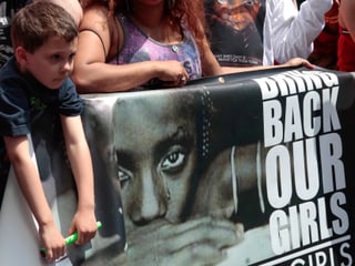 Eine Junge vor einem Plakat mit der Aufschrift: «Bring back our girls.»