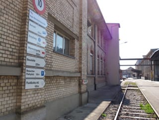 Ein Geleise führt an Wegweisern vorbei in das ehemalige Industrieareal Ein Geleise führt an Wegweisern vorbei in das ehemalige Industrieareal