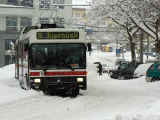 Ein Bus kämpft sich über die tiefverschneite Strasse.