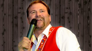 Ein Sänger mit rotem Gilet über einem weissen Hemd.