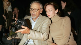 Hopper sitzt neben einer Frau und hält eine Foto-Kamera.