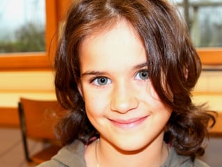 Aurelia, braune Haare, blaue Augen, im Klassenzimmer.