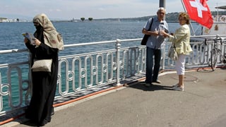 Frau mit Gesichtsschleier und starrendes älteres Schweizer Paar am See