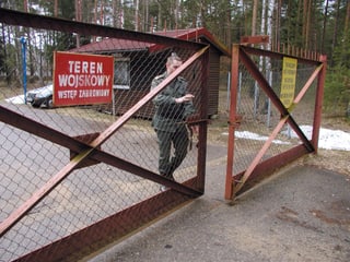 Soldat schliesst ein Gittertor auf einer Strasse