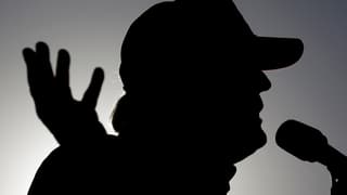 Umriss von Donald Trump, der in ein Mikrofon spricht.