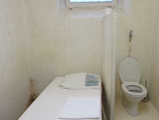 Eine Zelle mit einem Bett und einem WC.