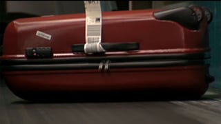 Roter Koffer auf einem Flughafen-Fliessband. Roter Koffer auf einem Flughafen-Fliessband.