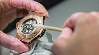 Ein Uhrenmacher baut eine Uhr zusammen.
