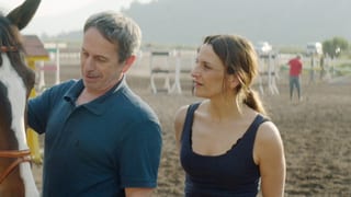 Ein Mann und eine Frau stehen auf einem Trainingsplatz für Pferde.