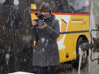 Eine Frau mit Videokamera im Schneetreiben.