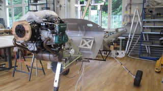 Motor und Fahrgestell eines Kleinzflugzeuges, das in einer Werkhalle zusammen gebaut wird. 