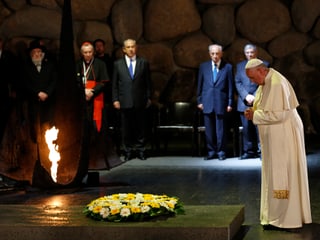 Papst steht vor einem Blumenkranz