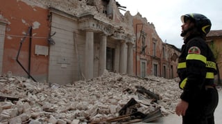 Feuerwehrmann blickt auf zerstörten Palazzo nach Beben in L'Aquila (Bild aus dem Jahr 2009). 