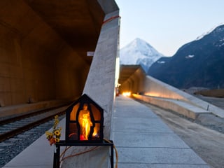 Tunneleingang mit einer beleuchteten Statue in einer Gedenkstätte.