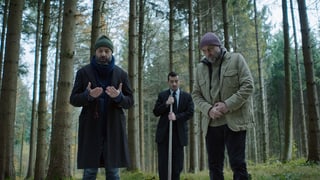 Drei Männer stehen im Wald