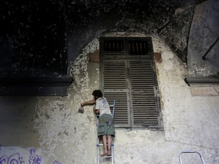 Mann arbeitet an einer Häuserfassade in Turin. 