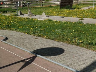 Minigolfanlage mit Unkraut zwischen den Steinplatten.