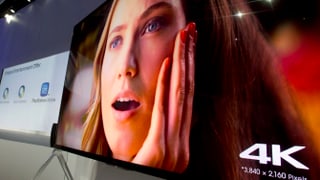 Ein 4K-Fernseher zeigt das Bild einer überrascht- und gutaussehenden jungen Frau.