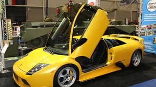 Ein gelber Lamborghini steht aufgeklappt da.