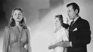Schwarzweissbild: Ein Mann und eine Frau schauen verängstigt auf eine andere Frau mit ausdruckslosem Gesicht.