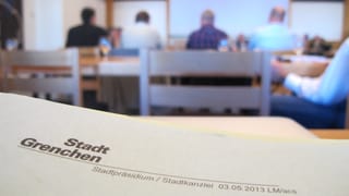 Im Hintergrund: Die Parlamentarier in der Sitzung. Im Vordergrund: Unterlagen der Sitzung des Gemeindeparlaments. Im Hintergrund: Die Parlamentarier in der Sitzung. Im Vordergrund: Unterlagen der Sitzung des Gemeindeparlaments.