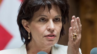 Portrait von Doris Leuthard, die gerade gestikuliert und die Hand vor dem Gesicht in die Höhe hält.