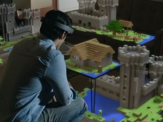 Mann sitzt vor einem Tisch, darauf ein virtuelles Schloss aus Bausteinen. Mann sitzt vor einem Tisch, darauf ein virtuelles Schloss aus Bausteinen.