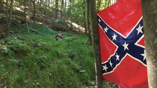 Ein Miliz-Soldat liegt im Wald, daneben hängt die Konföderierten-Flagge.