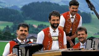 Die vier Volksmusikanten in Appenzeller Tracht musizieren im Freien.