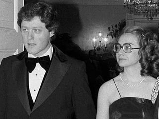 Bill Clinton und Hillary Rodham Clinton auf einer Schwarzweiss-Aufnahme: Sie gehen Hand in Hand in Abendgaderobe.