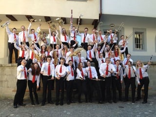 Die jungen Musikerinnen und Musiker mit weissen Hemden, roten Krawatten, schwarzen Hosen und Sonnenbrillen halten fröhlich ihre Instrumente in die Höhe.