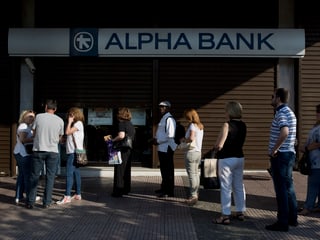 Menschen stehen Schlange vor einer Bank.