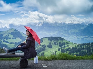 Asiatische Touristin mit Sonnenschirm auf der Rigi - im Hintergrund Berge und Vierwaldstättersee. 