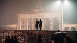 Berlin, Nov. 14, 1989: Zwei Sicherheitsleute auf der Berliner Mauer. Im Hintergrund ist das Brandenburger Tor zu sehen.