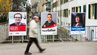 Ein Mann geht an Wahlplakaten vorbei.