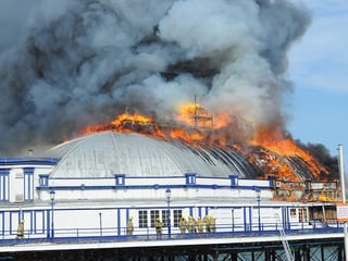 Ein Kuppelbau auf dem Pier brennt, viel Rauch steigt auf