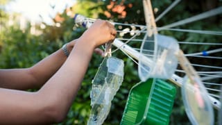 Eine junge Frau hängt Plastikschalen an eine Wäscheleine. Eine junge Frau hängt Plastikschalen an eine Wäscheleine.