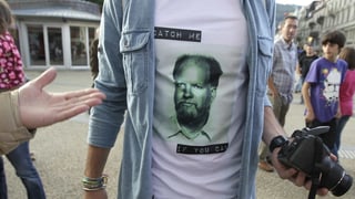 Mann zeigt ein T-Shirt mit Fahndungs-Foto von Herrn Kneubühl und dem Satz "Catch me if you can"