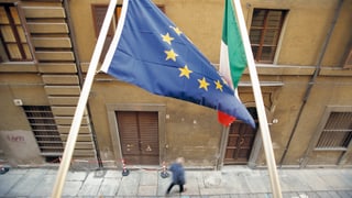EU- und Italienflagge hängen an der Fassade, Blick auf eine Gasse. EU- und Italienflagge hängen an der Fassade, Blick auf eine Gasse.