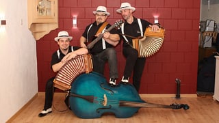 Gruppenbild mit drei Musikern, die schwarze Hemden und weisse Hüte tragen.